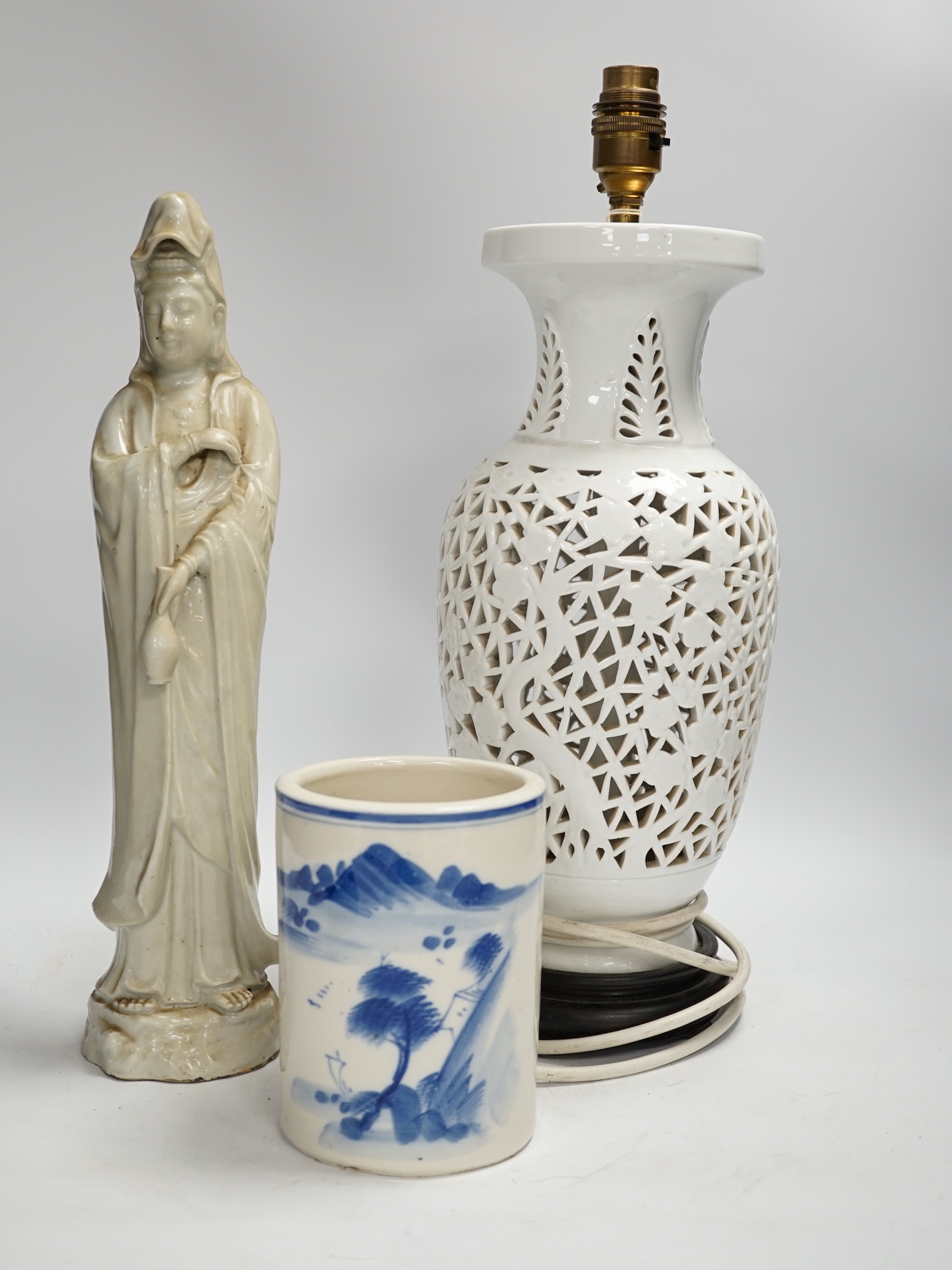 Chinese ceramics comprising blue and white brush washer, a blanc de chine pierced table lamp and figure of Guanyin, largest 42cm high